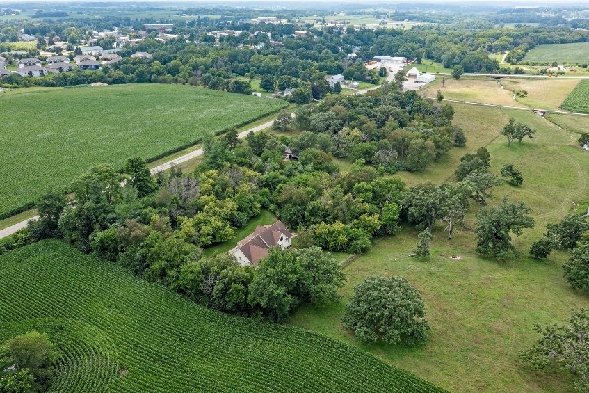 Aerial view of the home tucked into trees near open ground