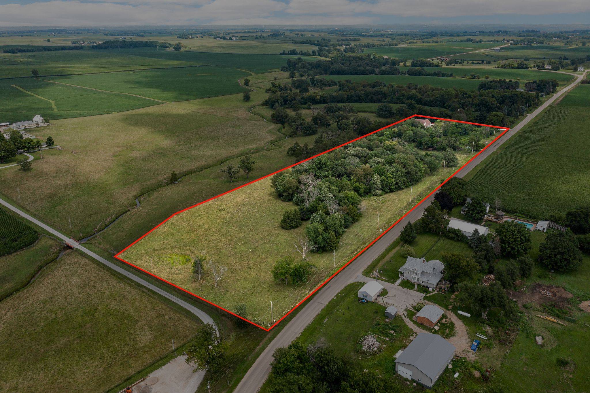 Aerial view from Sutliff Road showing the house, open ground, wooded setting, and an approximate red property outline