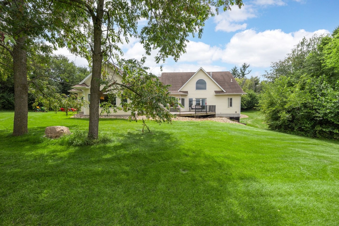 Rear of the home, back deck, and wooded lawn